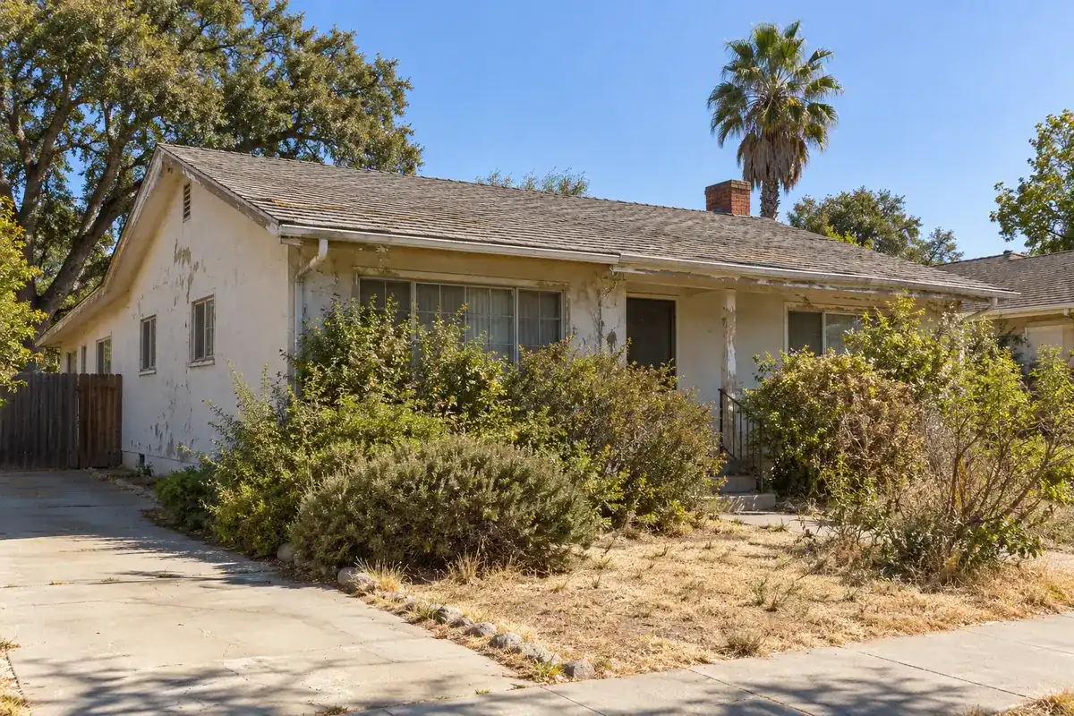 A house with peeling paint and worn roof shingles that needs repairs
